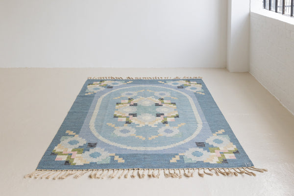 Ingo is a vintage rug handwoven in Sweden by textile designer Ingegerd Silow. Featuring a floral geometric pattern in blues. greens. pinks and black.