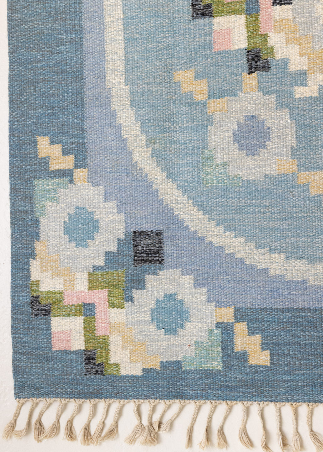 Ingo is a vintage rug handwoven in Sweden by textile designer Ingegerd Silow. Featuring a floral geometric pattern in blues. greens. pinks and black.