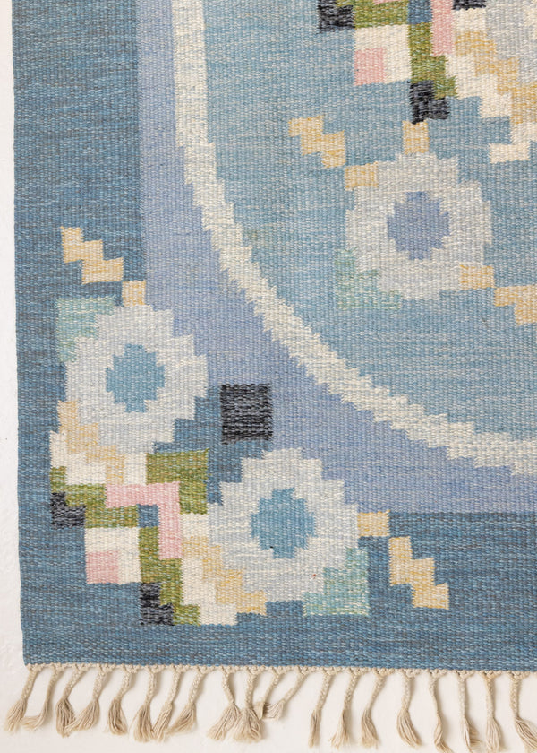 Ingo is a vintage rug handwoven in Sweden by textile designer Ingegerd Silow. Featuring a floral geometric pattern in blues. greens. pinks and black.
