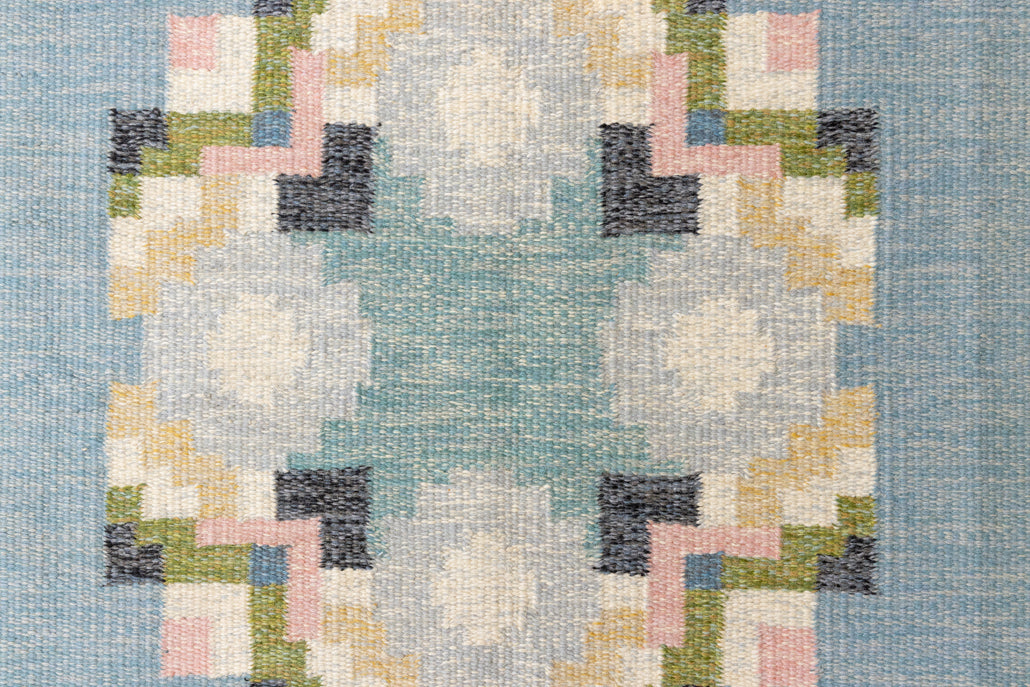 Ingo is a vintage rug handwoven in Sweden by textile designer Ingegerd Silow. Featuring a floral geometric pattern in blues. greens. pinks and black.
