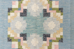 Ingo is a vintage rug handwoven in Sweden by textile designer Ingegerd Silow. Featuring a floral geometric pattern in blues. greens. pinks and black.