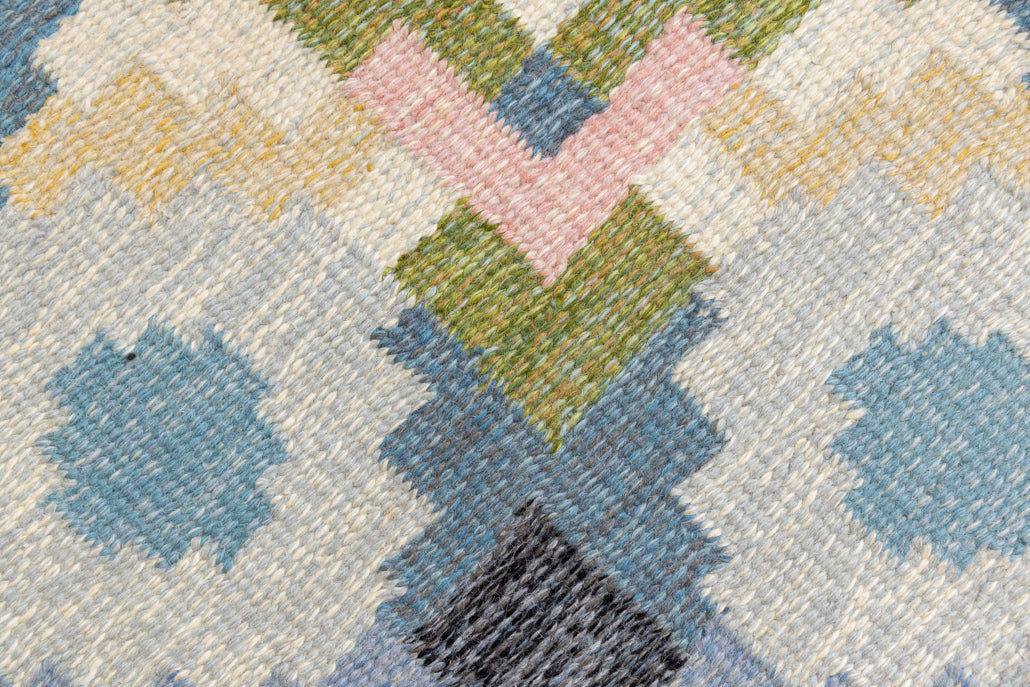 Ingo is a vintage rug handwoven in Sweden by textile designer Ingegerd Silow. Featuring a floral geometric pattern in blues. greens. pinks and black.