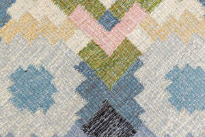 Ingo is a vintage rug handwoven in Sweden by textile designer Ingegerd Silow. Featuring a floral geometric pattern in blues. greens. pinks and black.