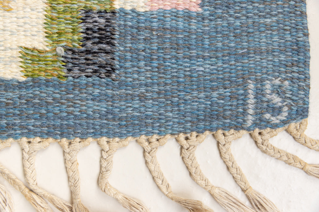 Ingo is a vintage rug handwoven in Sweden by textile designer Ingegerd Silow. Featuring a floral geometric pattern in blues. greens. pinks and black.