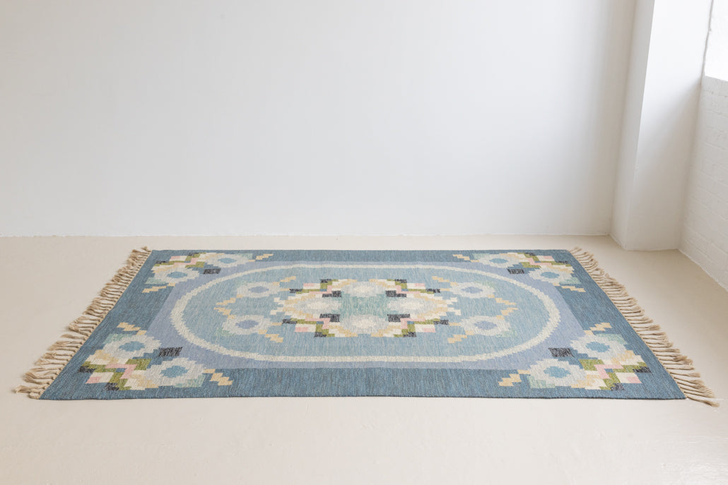 Ingo is a vintage rug handwoven in Sweden by textile designer Ingegerd Silow. Featuring a floral geometric pattern in blues. greens. pinks and black.