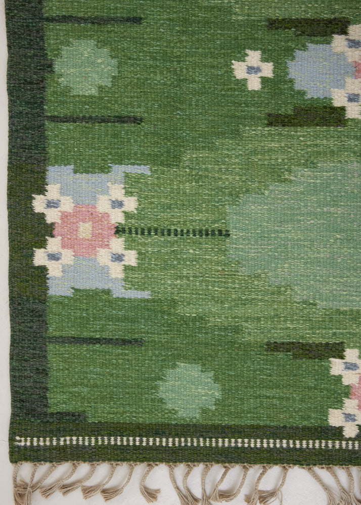 a vintage rug handwoven in Sweden by  textile designer Ingegerd Silow. Green in colour featuring a rare geometric floral motif