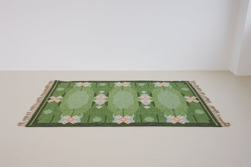 a vintage rug handwoven in Sweden by  textile designer Ingegerd Silow. Green in colour featuring a rare geometric floral motif