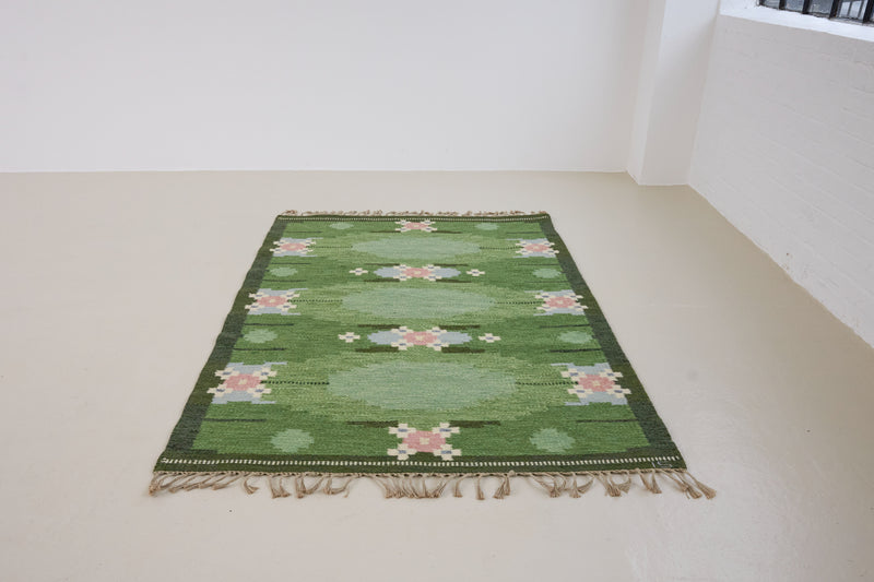a vintage rug handwoven in Sweden by  textile designer Ingegerd Silow. Green in colour featuring a rare geometric floral motif