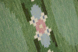 a vintage rug handwoven in Sweden by  textile designer Ingegerd Silow. Green in colour featuring a rare geometric floral motif