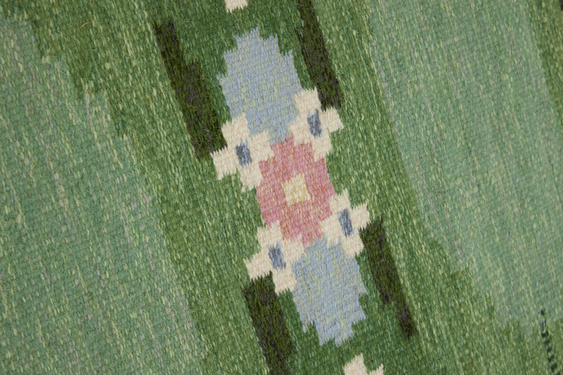 a vintage rug handwoven in Sweden by  textile designer Ingegerd Silow. Green in colour featuring a rare geometric floral motif
