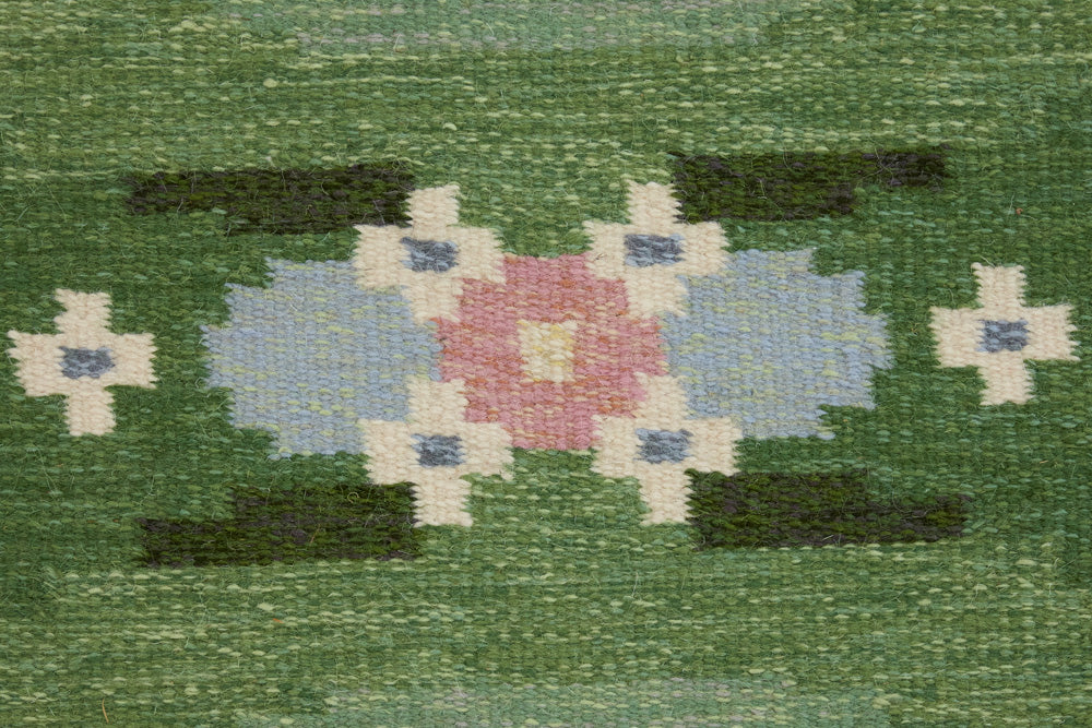 a vintage rug handwoven in Sweden by  textile designer Ingegerd Silow. Green in colour featuring a rare geometric floral motif