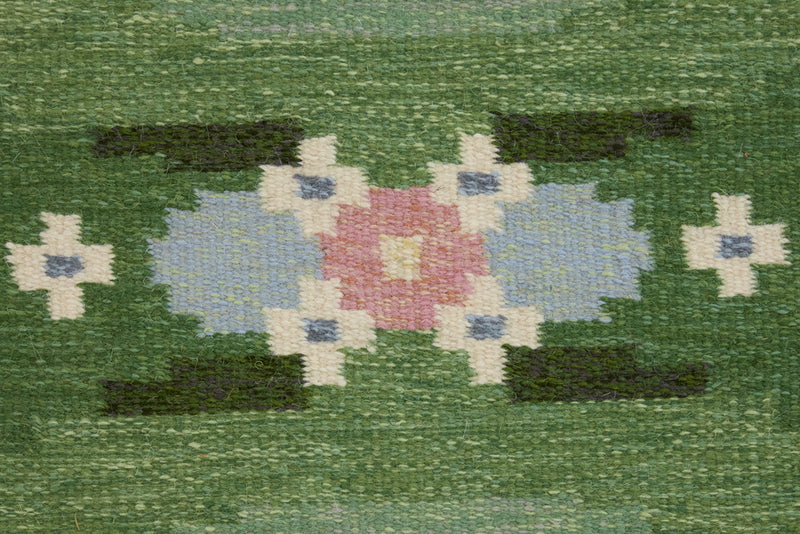 a vintage rug handwoven in Sweden by  textile designer Ingegerd Silow. Green in colour featuring a rare geometric floral motif