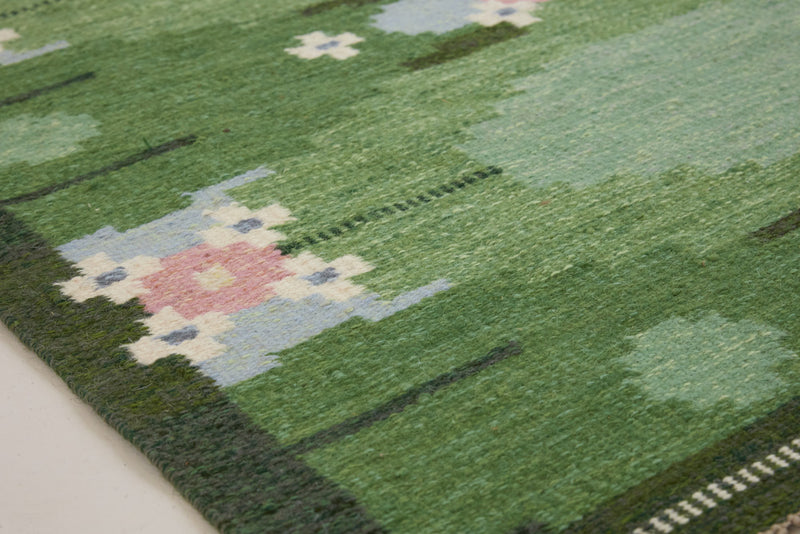 a vintage rug handwoven in Sweden by  textile designer Ingegerd Silow. Green in colour featuring a rare geometric floral motif