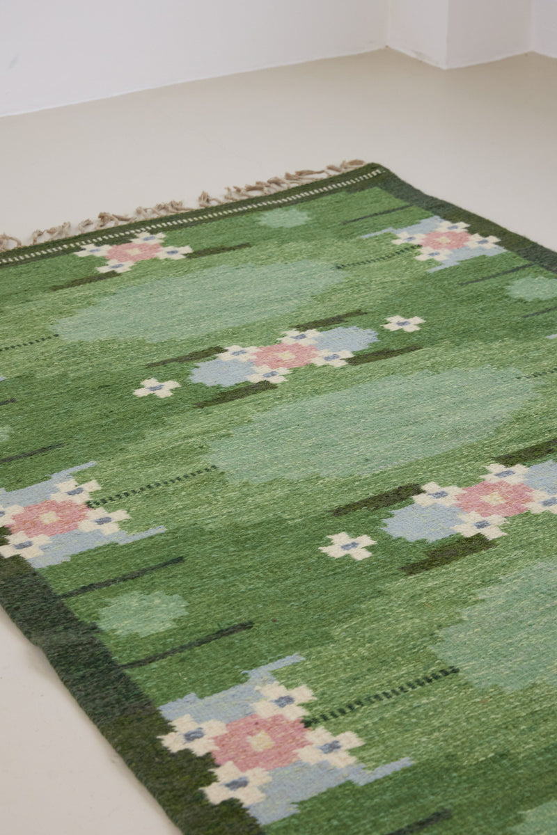 a vintage rug handwoven in Sweden by  textile designer Ingegerd Silow. Green in colour featuring a rare geometric floral motif