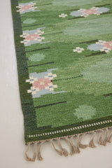 a vintage rug handwoven in Sweden by  textile designer Ingegerd Silow. Green in colour featuring a rare geometric floral motif
