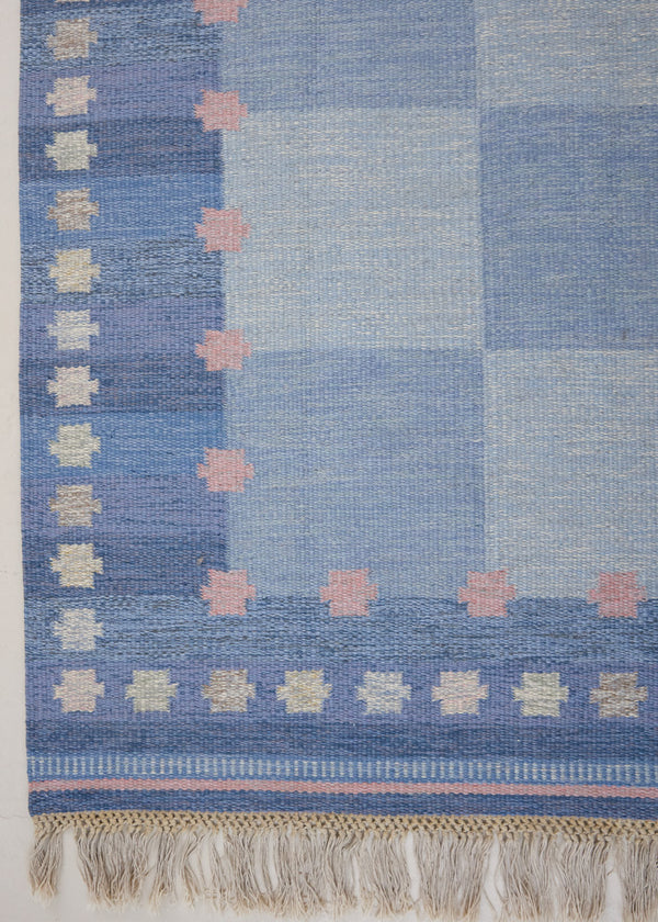 an original Swedish röllakan rug handwoven by mid-century textile designer Anna Johanna Angström. Her colourful kilim features strong lines in a blue and pale blue checkered pattern with accents of pink and cream