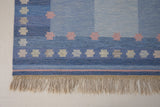 an original Swedish röllakan rug handwoven by mid-century textile designer Anna Johanna Angström. Her colourful kilim features strong lines in a blue and pale blue checkered pattern with accents of pink and cream