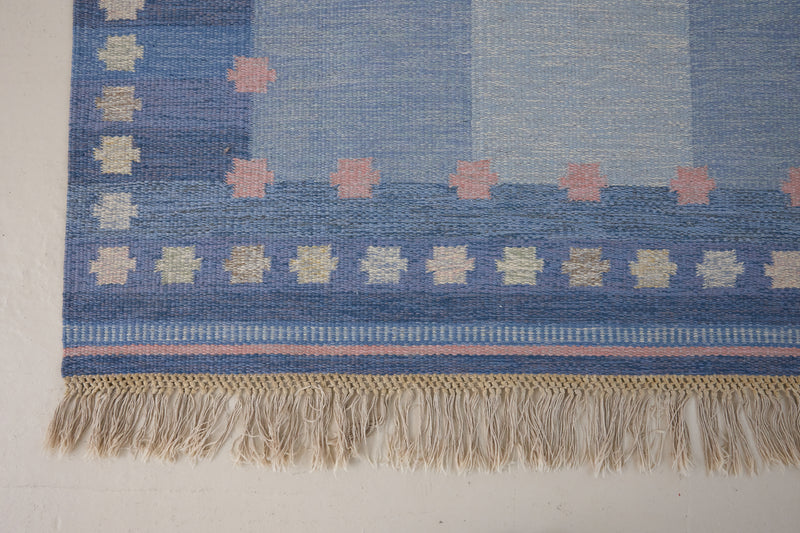 an original Swedish röllakan rug handwoven by mid-century textile designer Anna Johanna Angström. Her colourful kilim features strong lines in a blue and pale blue checkered pattern with accents of pink and cream