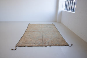 Textured thick pile antique Moroccan rug with a geometric pattern on a peach background