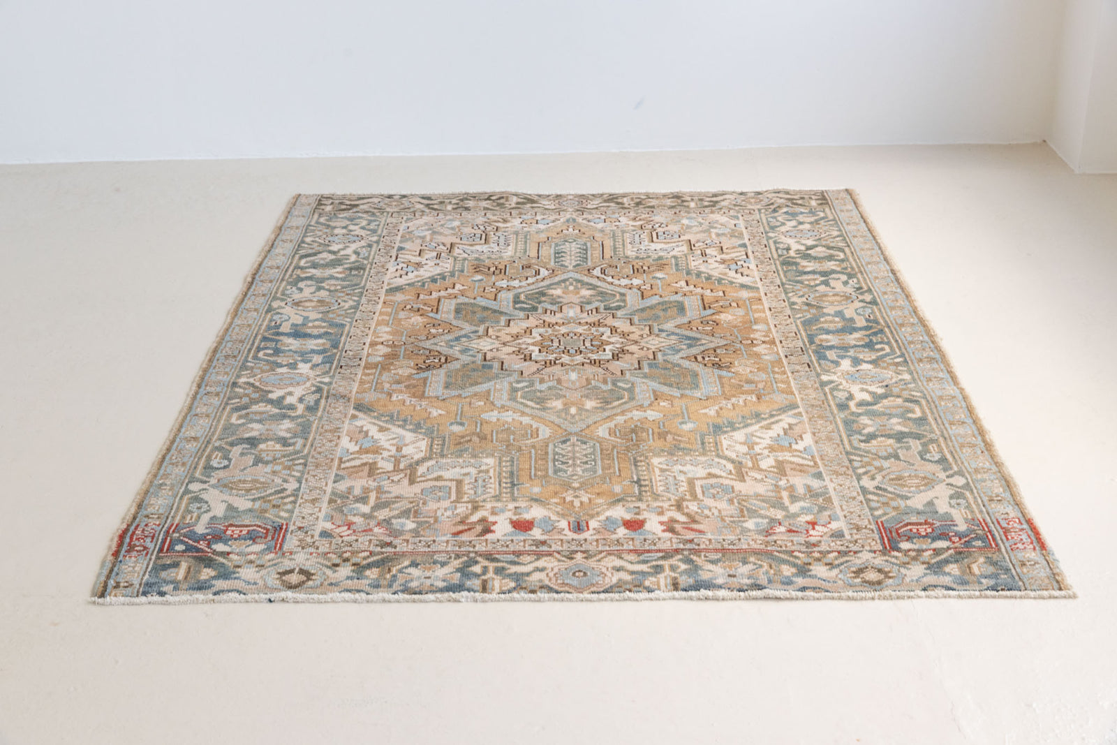 This is a vintage Persian Heriz rug. With a unique antique wash, this carpet boasts a muted palette in soft blue with flashes of red and brown