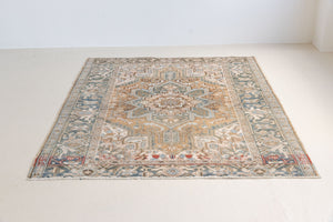 This is a vintage Persian Heriz rug. With a unique antique wash, this carpet boasts a muted palette in soft blue with flashes of red and brown