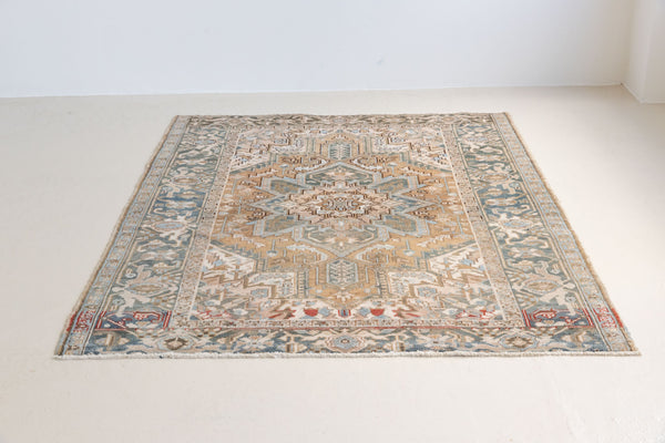 This is a vintage Persian Heriz rug. With a unique antique wash, this carpet boasts a muted palette in soft blue with flashes of red and brown