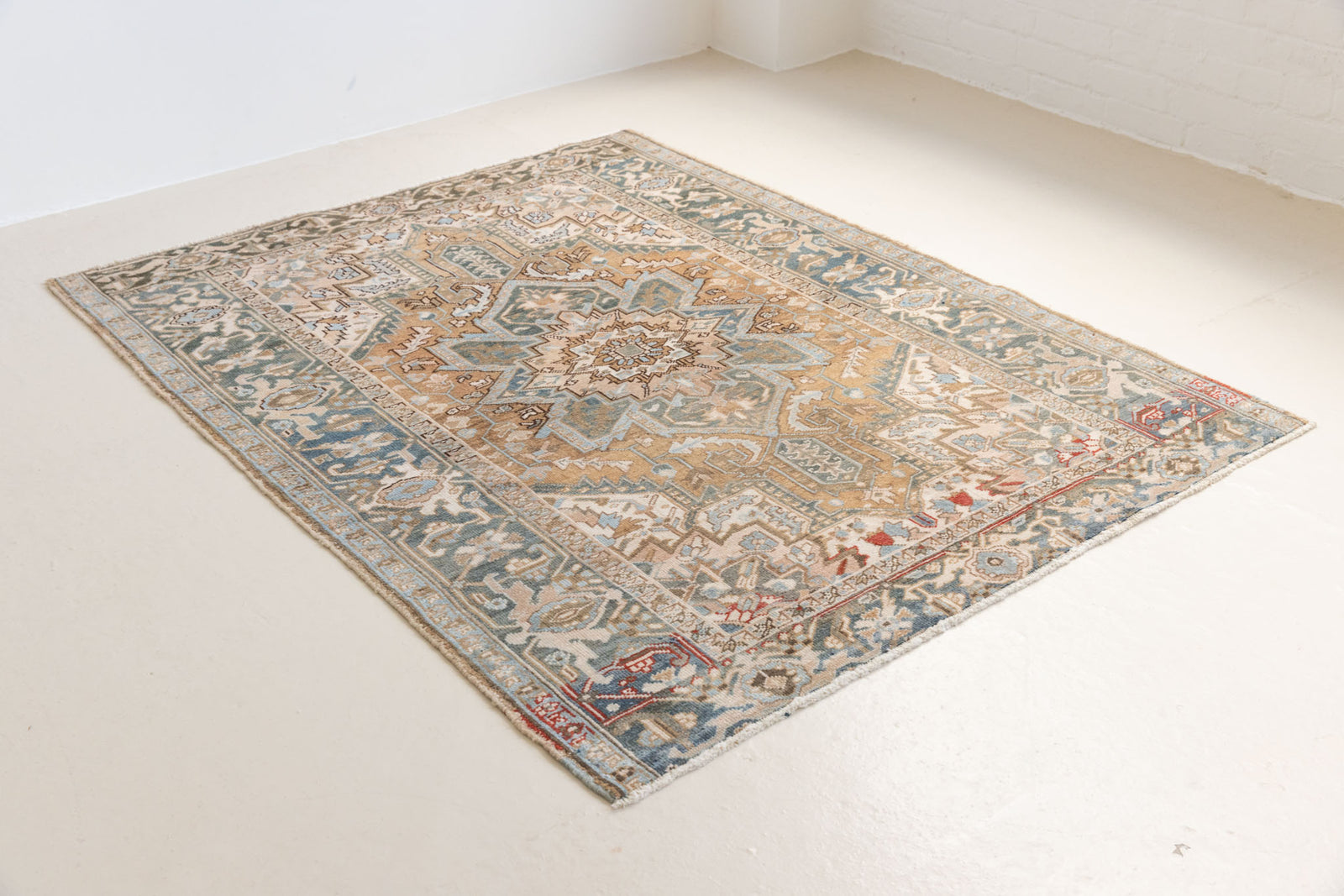 This is a vintage Persian Heriz rug. With a unique antique wash, this carpet boasts a muted palette in soft blue with flashes of red and brown