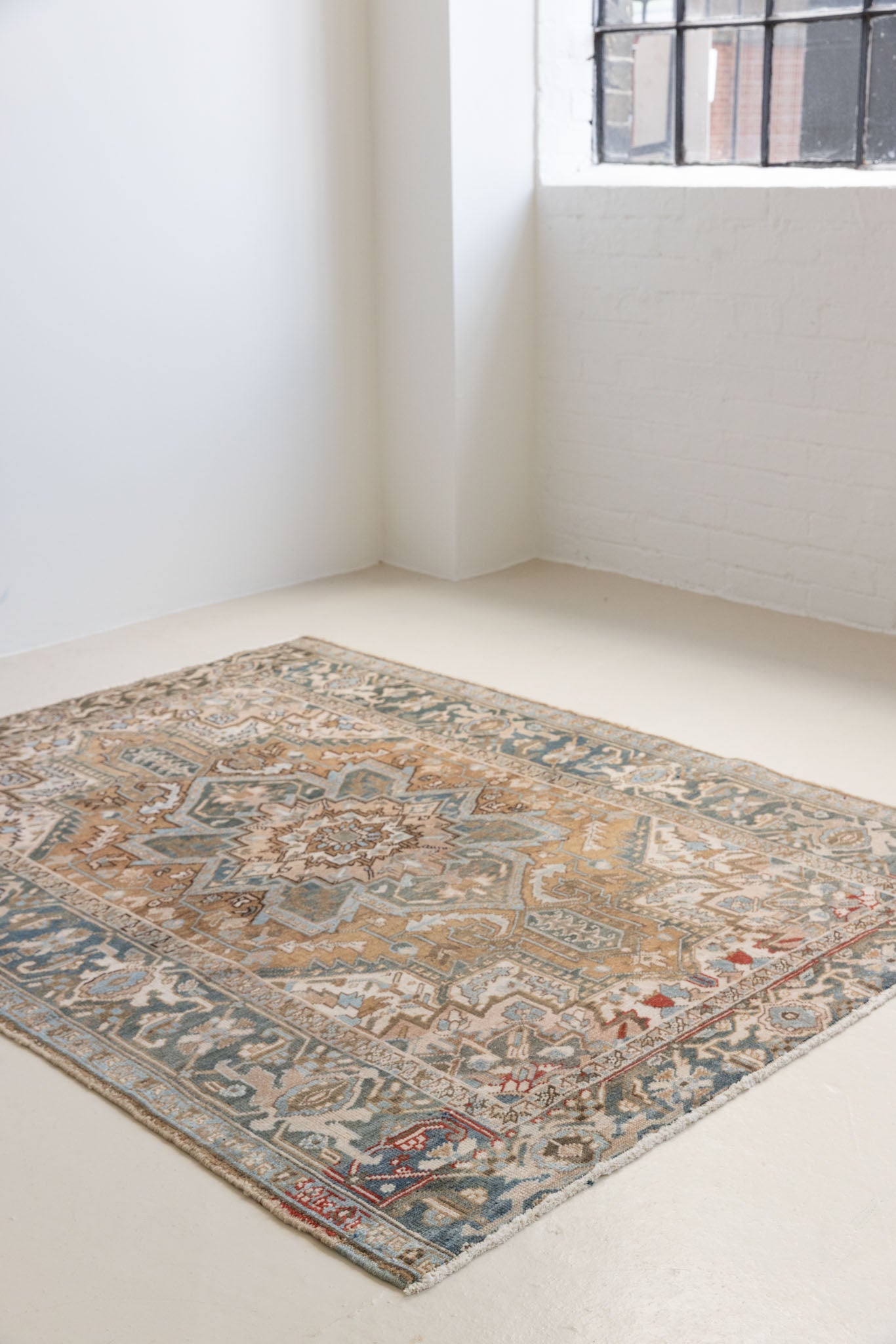 This is a vintage Persian Heriz rug. With a unique antique wash, this carpet boasts a muted palette in soft blue with flashes of red and brown