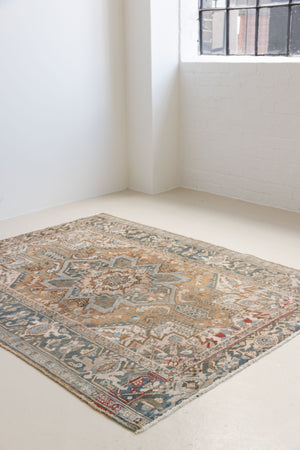 This is a vintage Persian Heriz rug. With a unique antique wash, this carpet boasts a muted palette in soft blue with flashes of red and brown