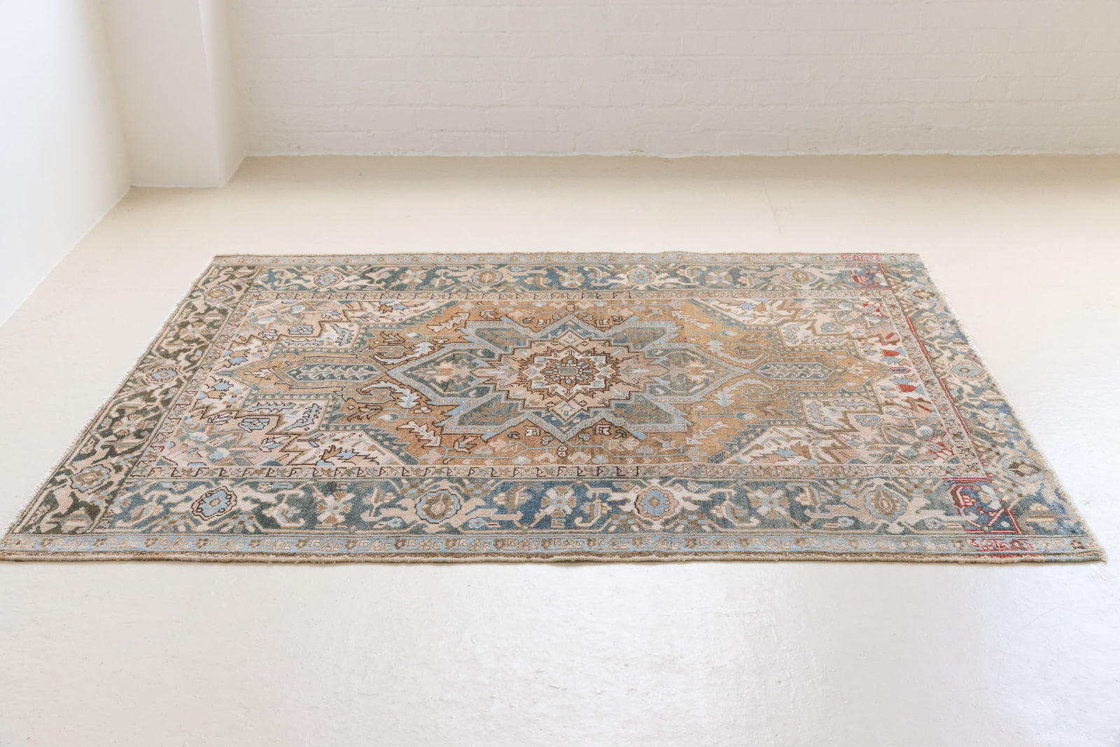 This is a vintage Persian Heriz rug. With a unique antique wash, this carpet boasts a muted palette in soft blue with flashes of red and brown
