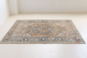 This is a vintage Persian Heriz rug. With a unique antique wash, this carpet boasts a muted palette in soft blue with flashes of red and brown