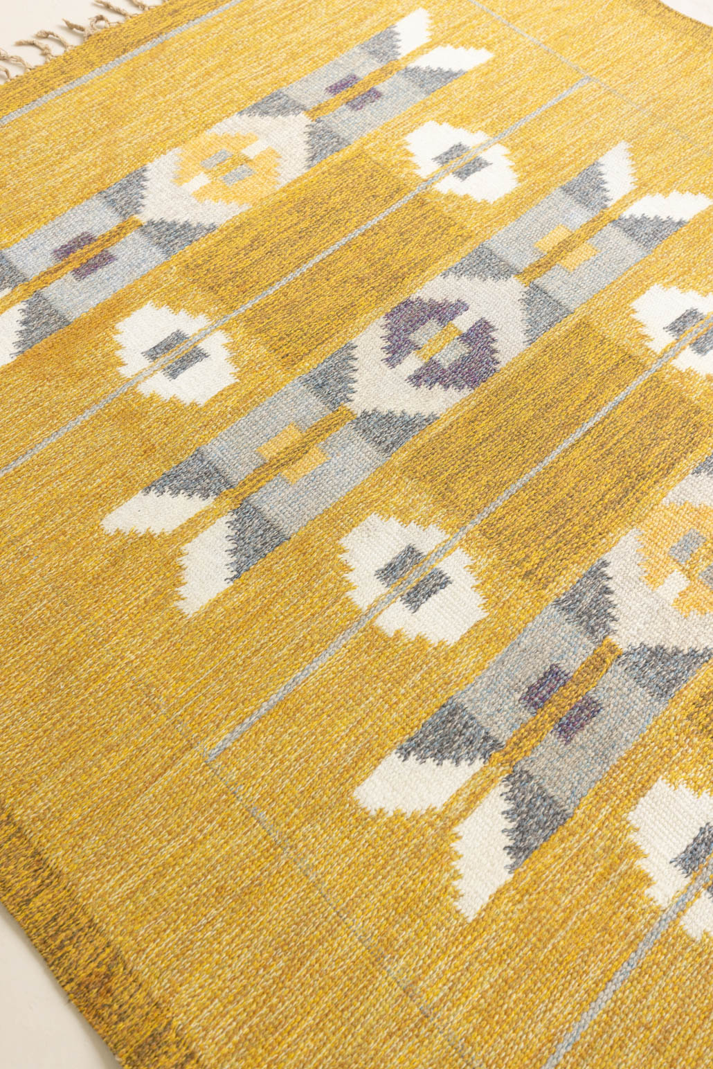 Eliza is a röllakan rug handwoven by textile designer Ingegerd Silow. Featuring a yellow, white and grey pattern