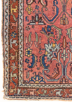 This Vintage rug was handwoven in a small village in Western Persia and features floral and geometric patterns and hints of pink and blue.