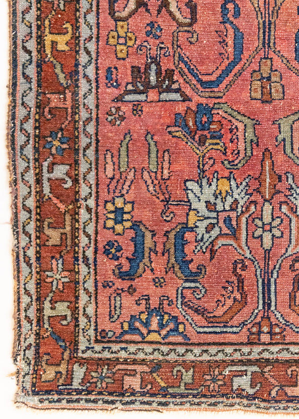 This Vintage rug was handwoven in a small village in Western Persia and features floral and geometric patterns and hints of pink and blue.